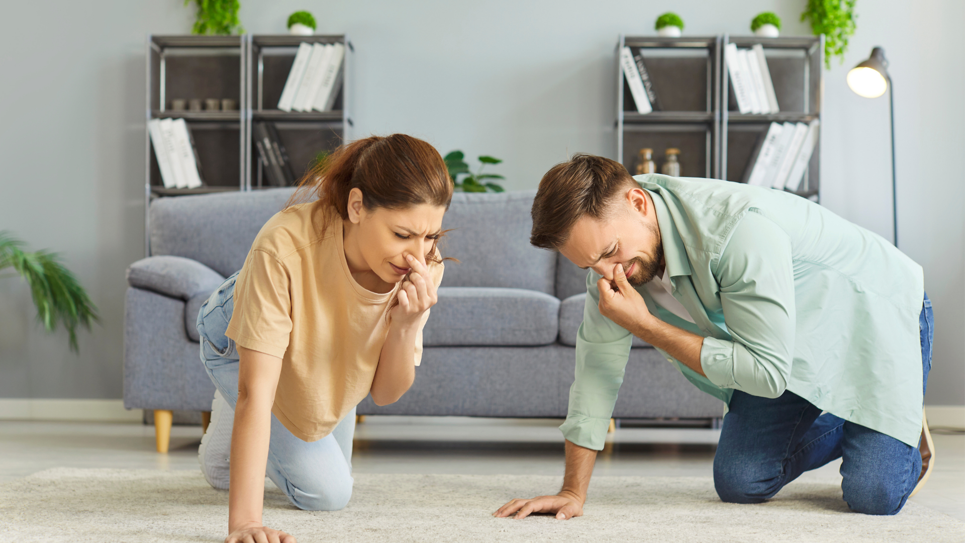 Woman and man kneeling on carpet, covering noses, distressed expression. Living room.