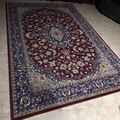 Red and blue oriental rug with a floral pattern, set on tiled floor.