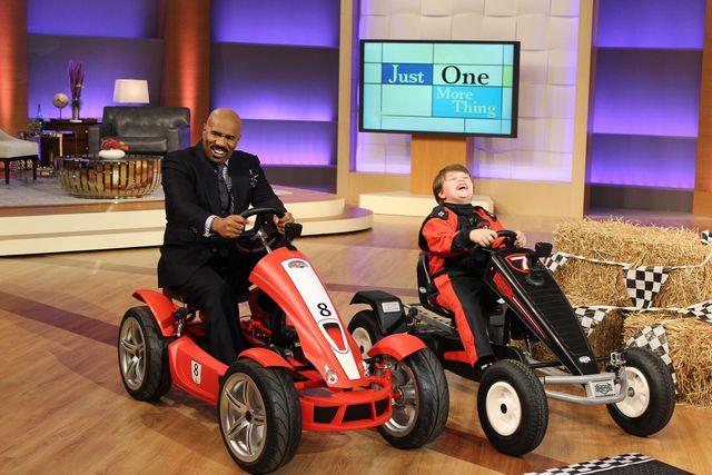 A man and a boy are riding go karts on a stage.