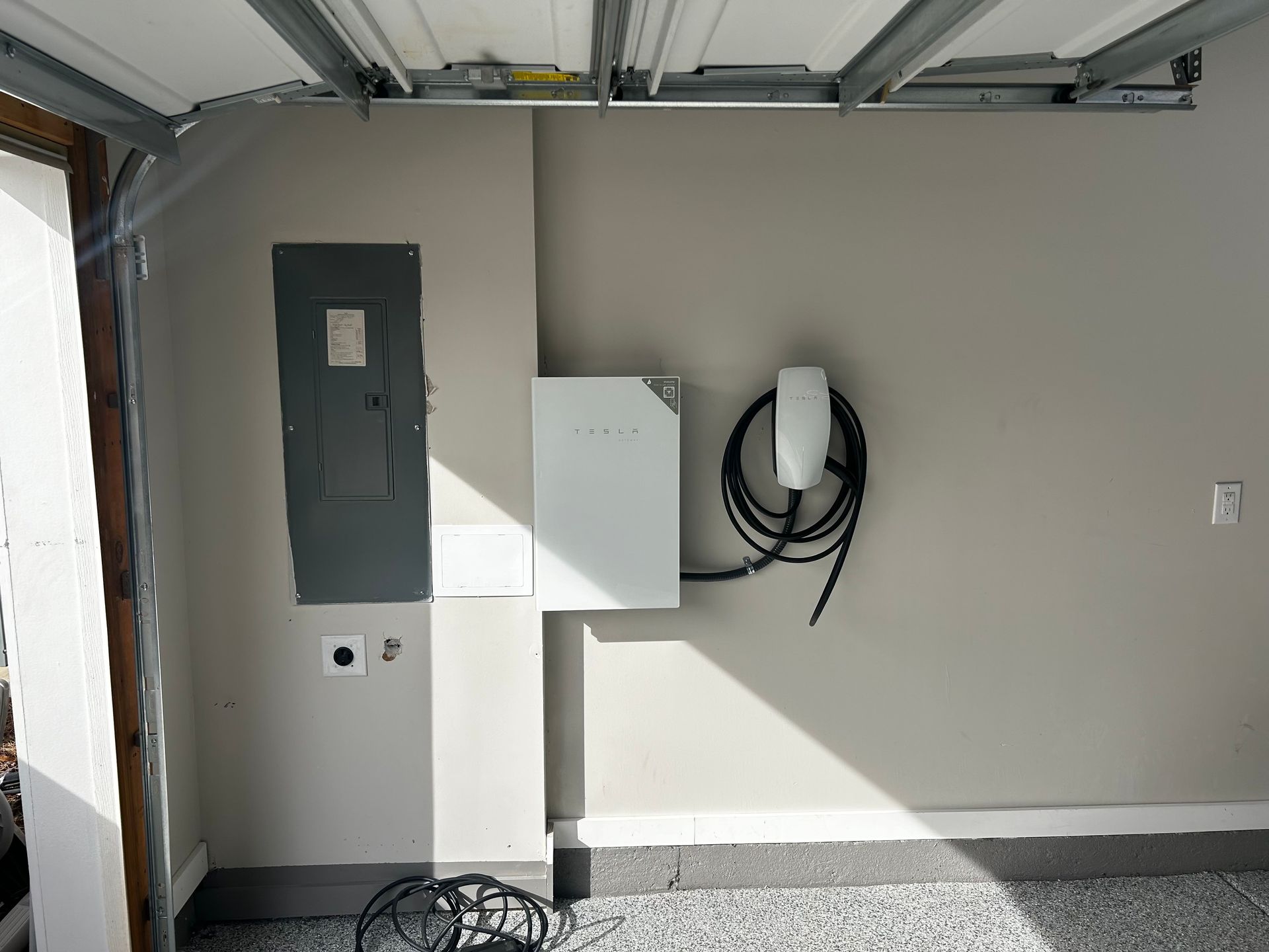 Garage interior with electrical panel, Tesla charger, and solar panel.