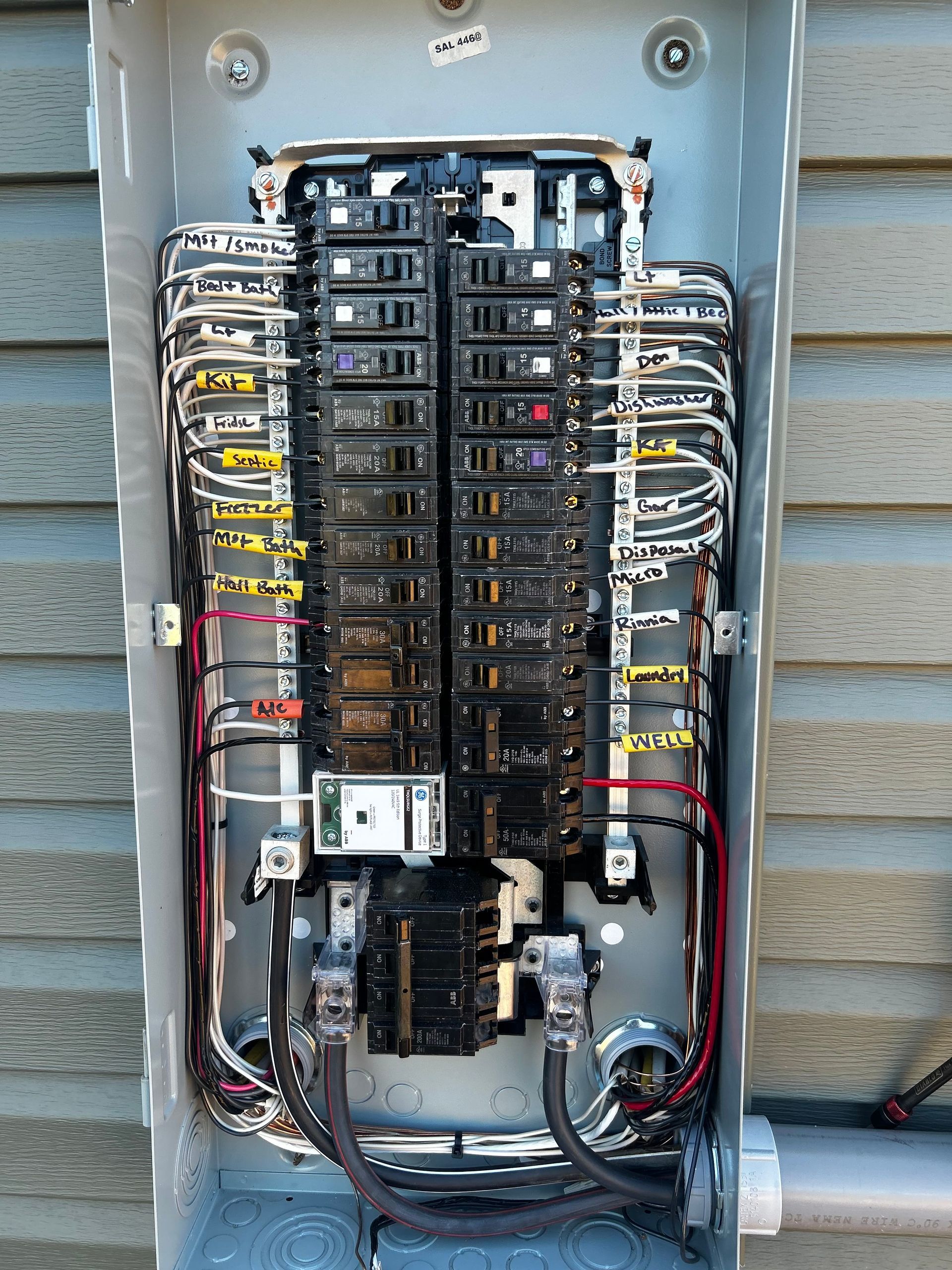 Open electrical panel with multiple circuit breakers and wires.