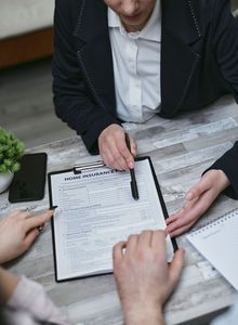 Hands reviewing a clipboard checklist at a table with papers and a pen