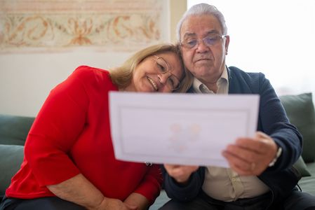 Couple on a couch holding a blank card and smiling together