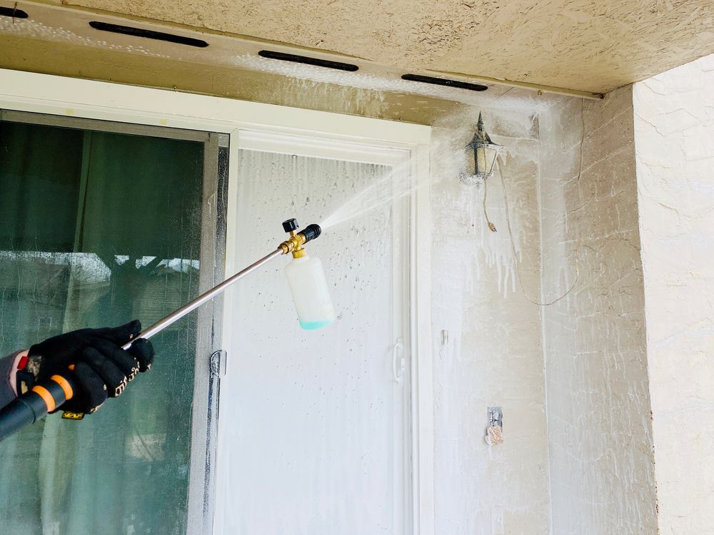 A Person Is Spraying A Wall With A Sprayer — Jervis Bay Pressure Washing & Property Maintenance In Sanctuary Point, NSW