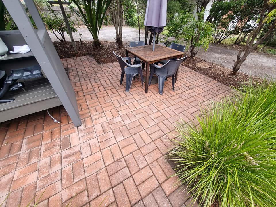 A Patio With A Table And Chairs And An Umbrella Cleaned — Jervis Bay Pressure Washing & Property Maintenance In Berry, NSW