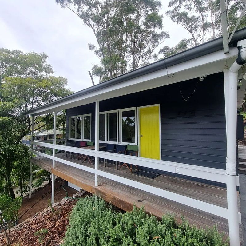 Black House With A Yellow Door And White Railing — Jervis Bay Pressure Washing & Property Maintenance in Sanctuary Point, NSW