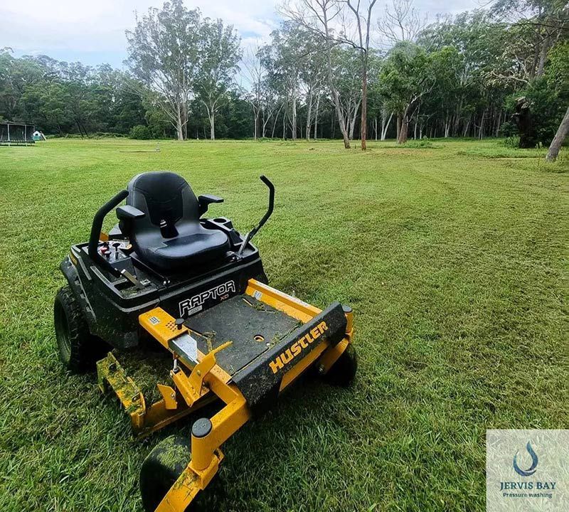 A Hustler Lawn Mower Is Sitting In The Grass — Jervis Bay Pressure Washing & Property Maintenance in Sanctuary Point, NSW