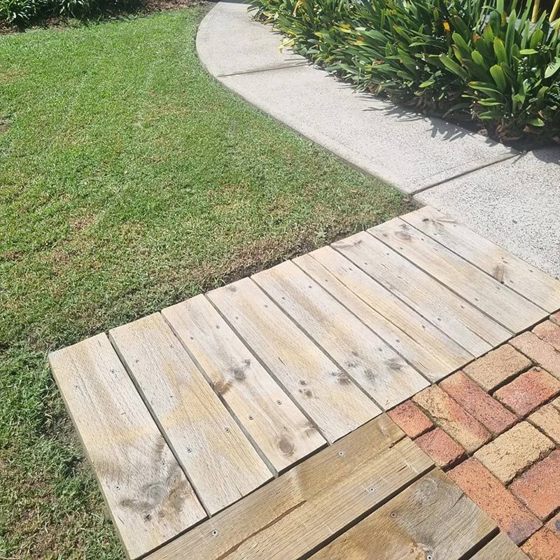 A Wooden Walkway And Brick With New Cleaned Lawn — Jervis Bay Pressure Washing & Property Maintenance in Sanctuary Point, NSW