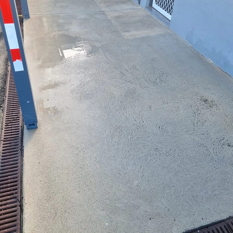 A Concrete Walkway Next To A Building With A Drain — Jervis Bay Pressure Washing & Property Maintenance in Culburra, NSW