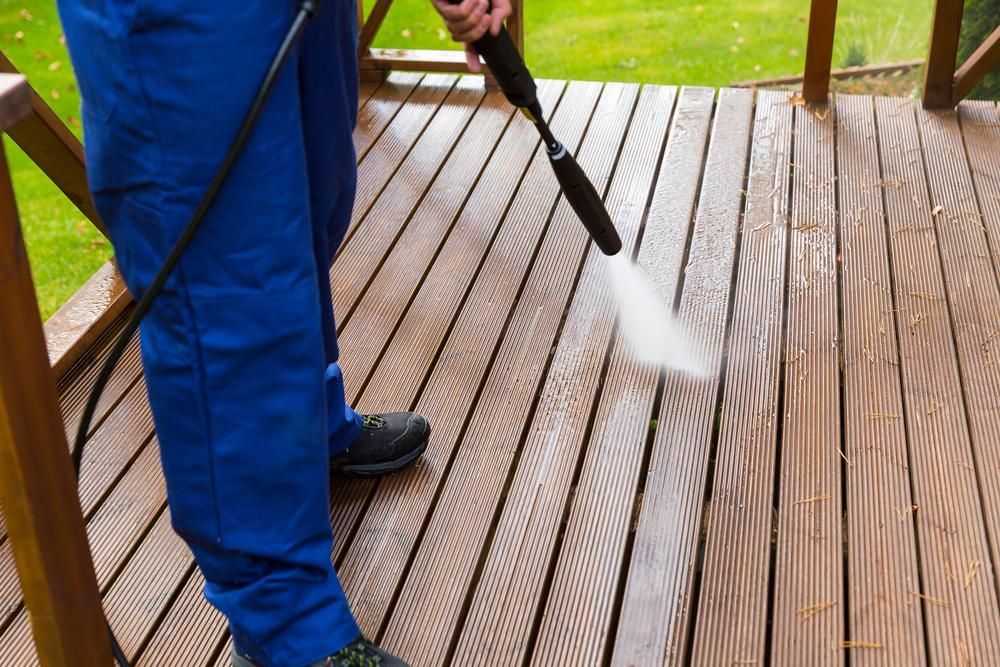 Person Is Using Pressure Washer To Clean A Wooden Deck — Jervis Bay Pressure Washing & Property Maintenance In Bomaderry, NSW
