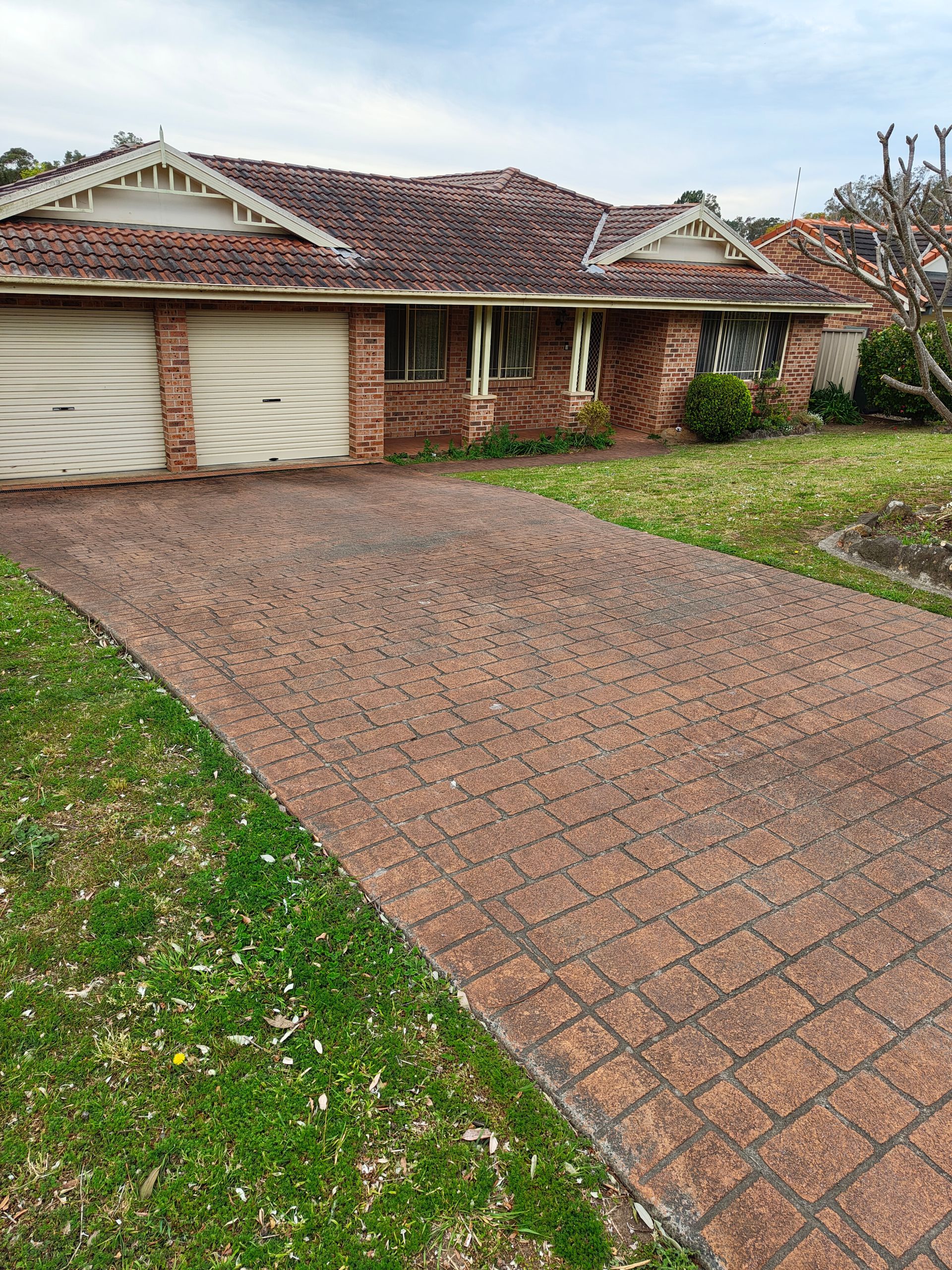 A Dirty Driveway Leading To A Brick House — Jervis Bay Pressure Washing & Property Maintenance in Sanctuary Point, NSW