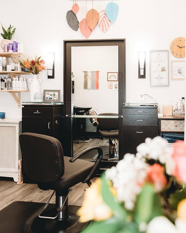Stylish salon with black chairs, mirror, shelves, and pastel wall decor in a bright room