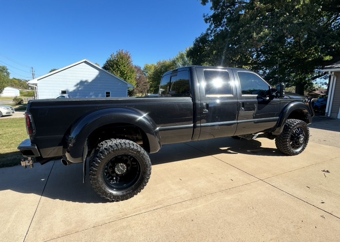 Black lifted pickup truck parked on a driveway in bright daylight