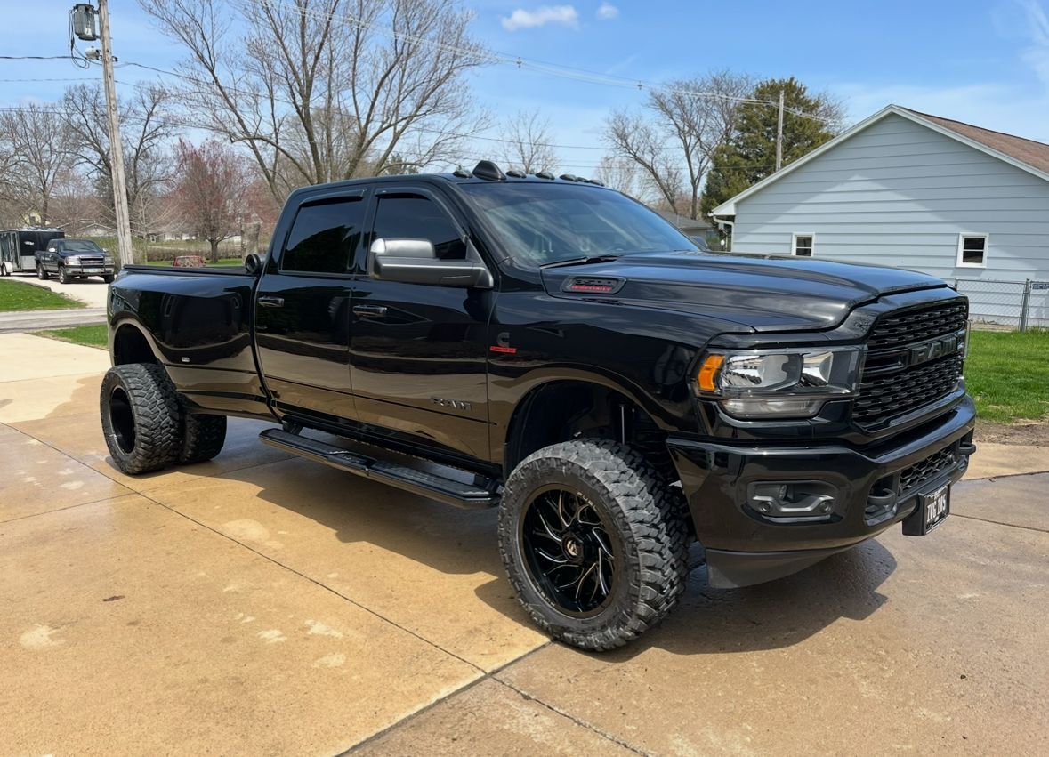 Black lifted pickup truck parked in a driveway on a sunny day