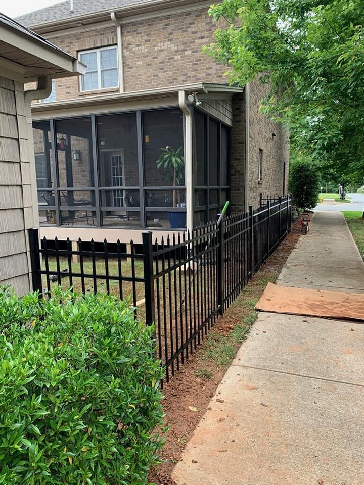 Apartment building with screened porch, black fence, and sidewalk along a tree-lined walkway