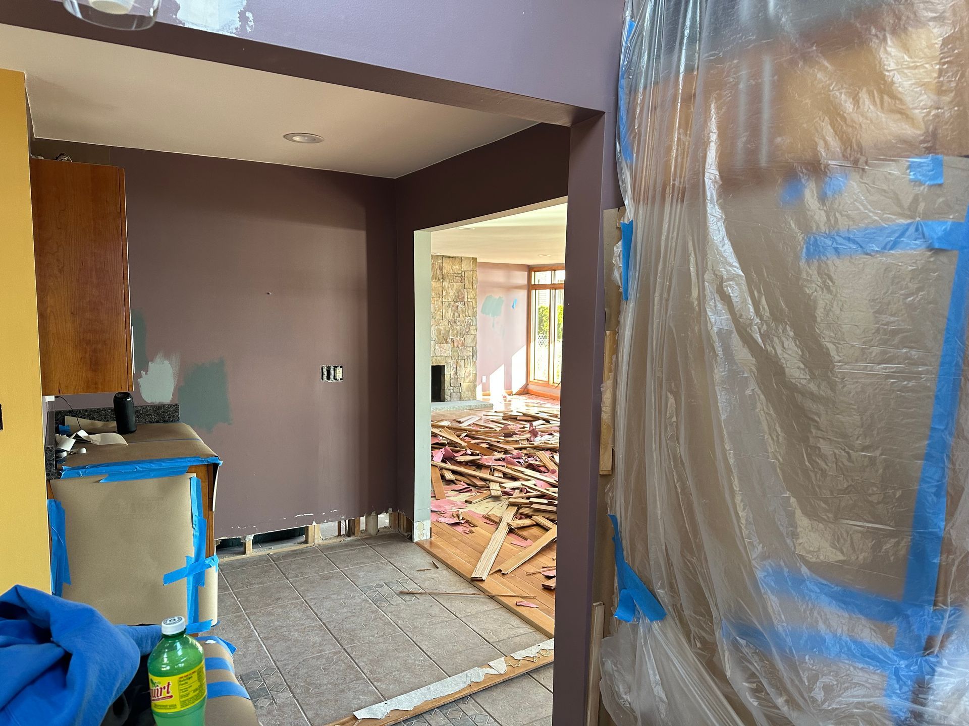 A room under renovation with dark walls, plastic sheeting covering an opening, and construction debris on the floor.