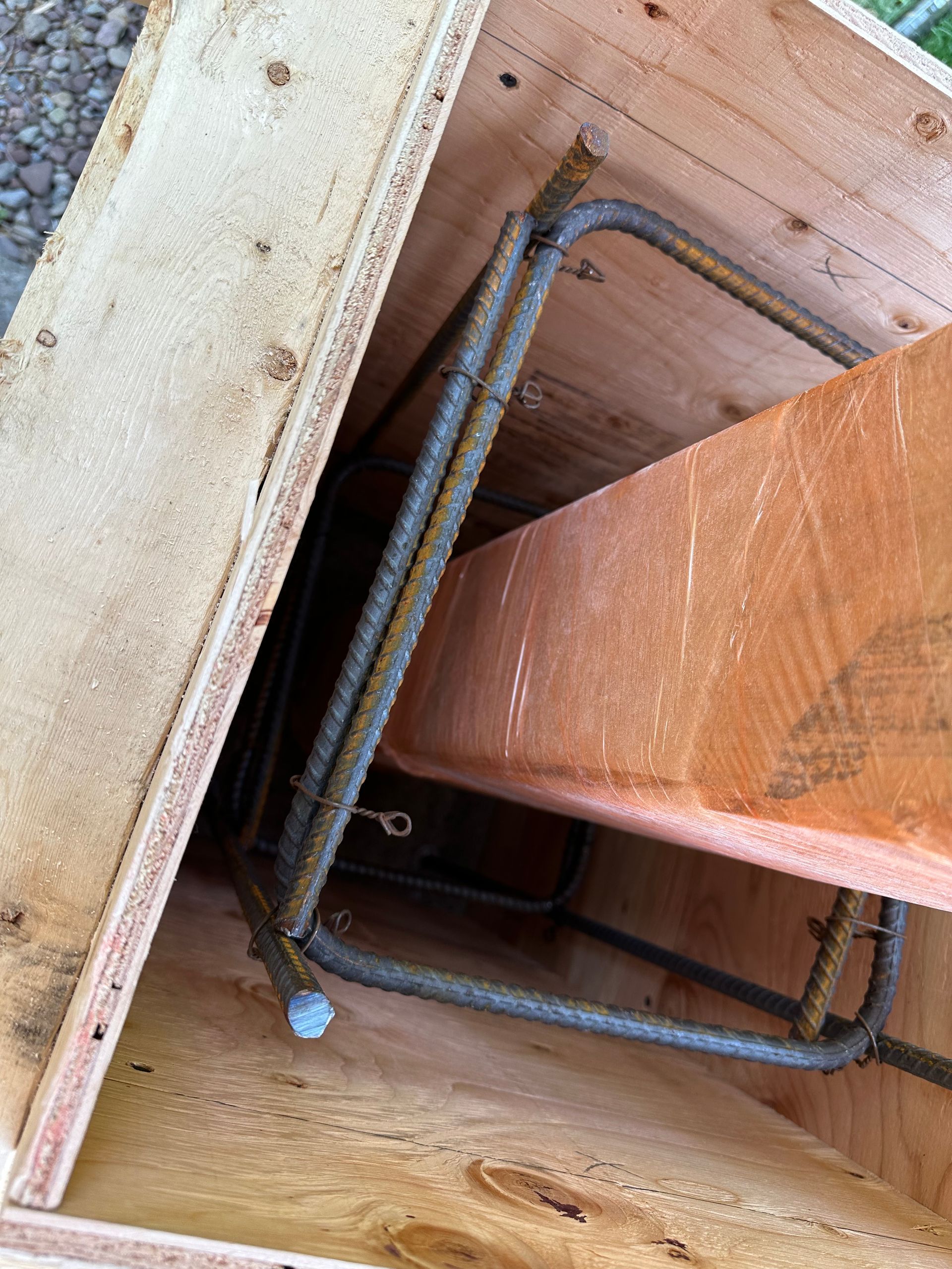 A wooden form for a concrete column contains a steel rebar cage reinforced around a centered wooden post.