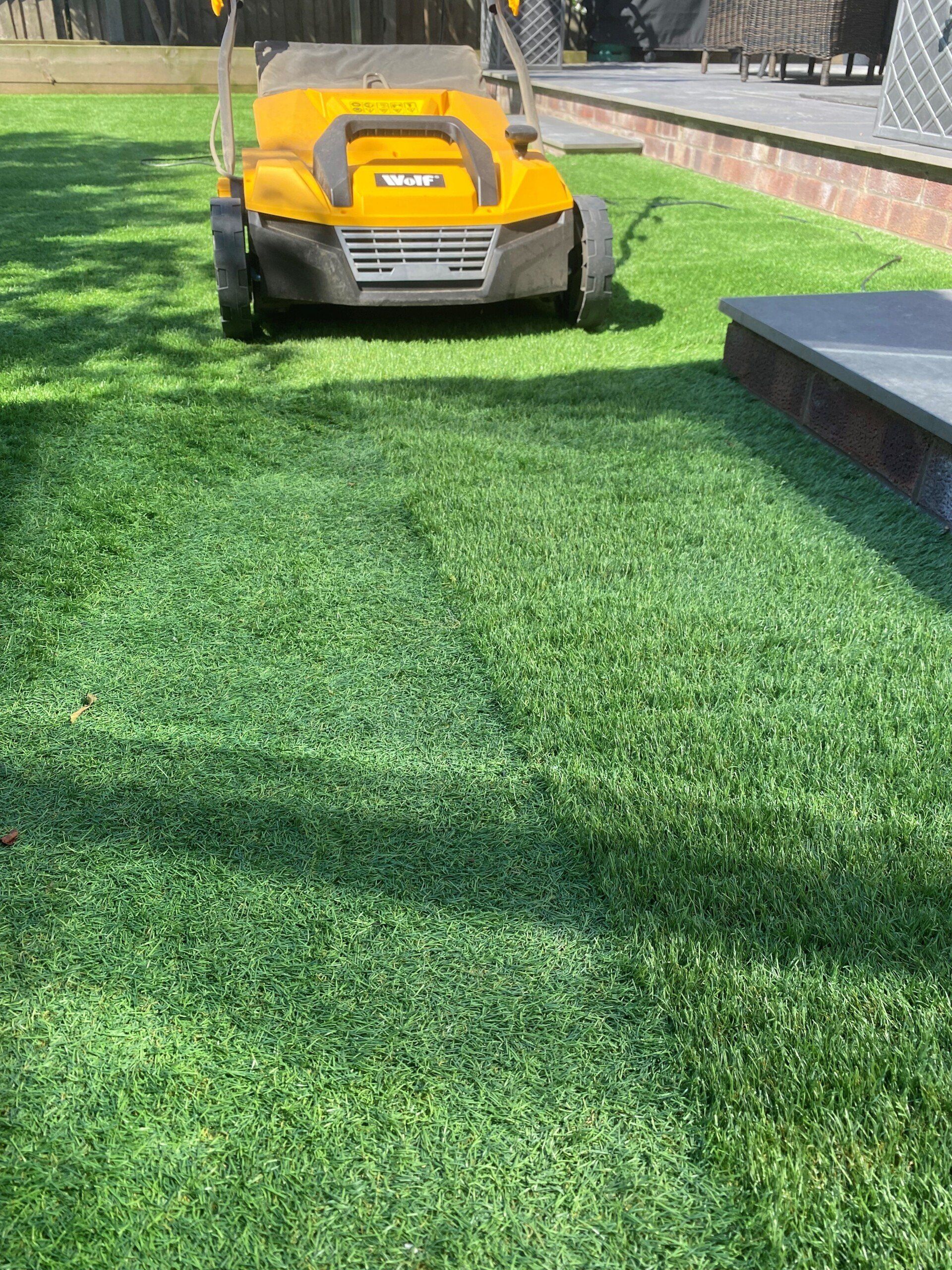 a yellow lawn mower is cutting a lush green lawn .