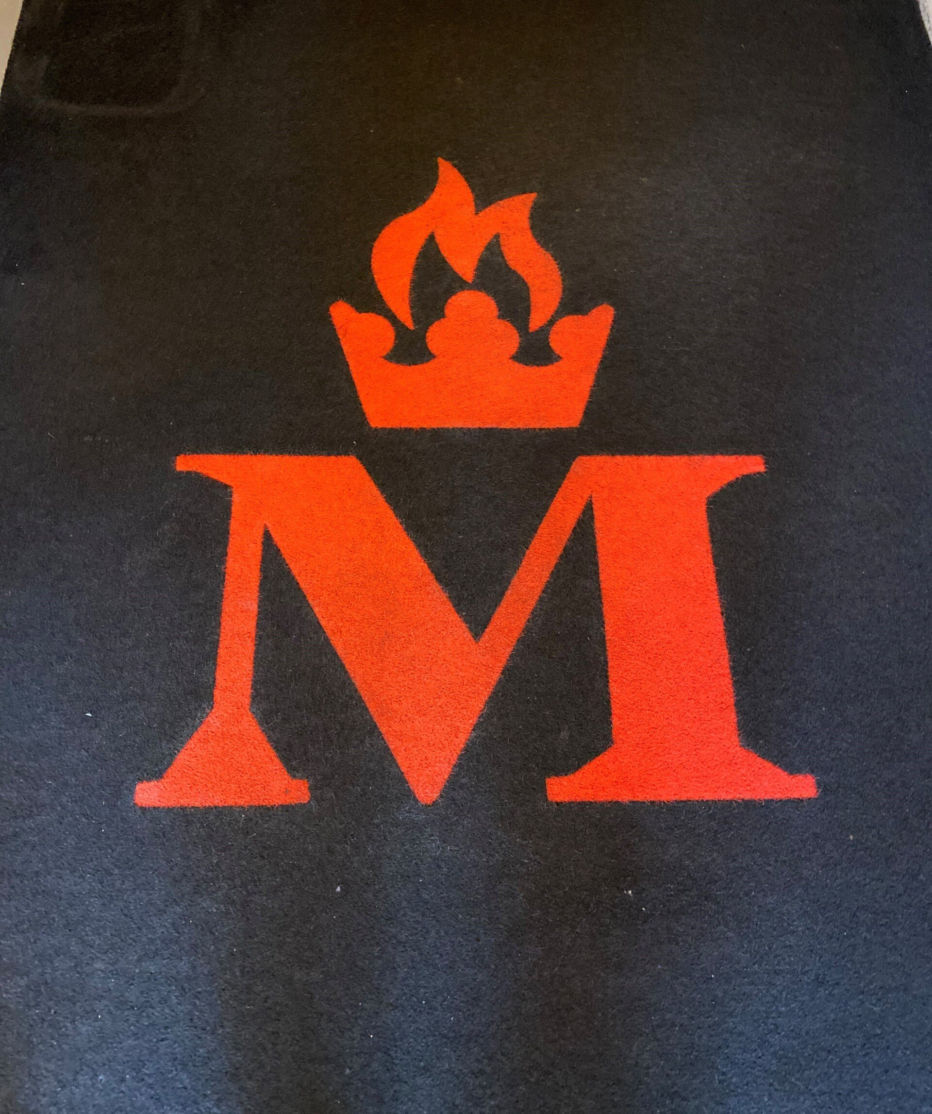 a red letter m with a crown on top of it