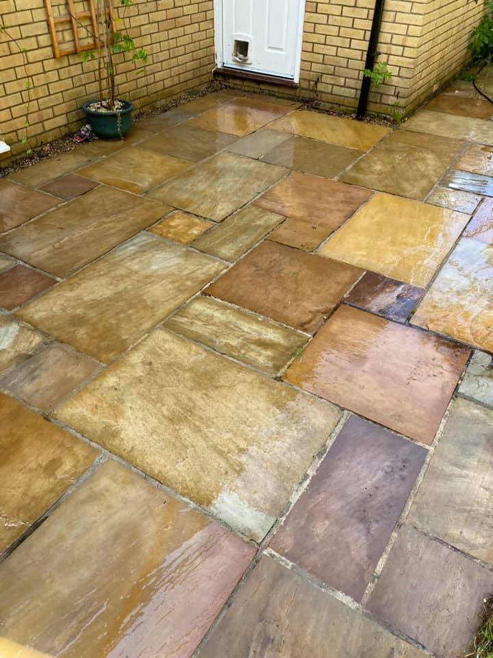 a patio with a cat door and a brick wall in the background, after cleaning