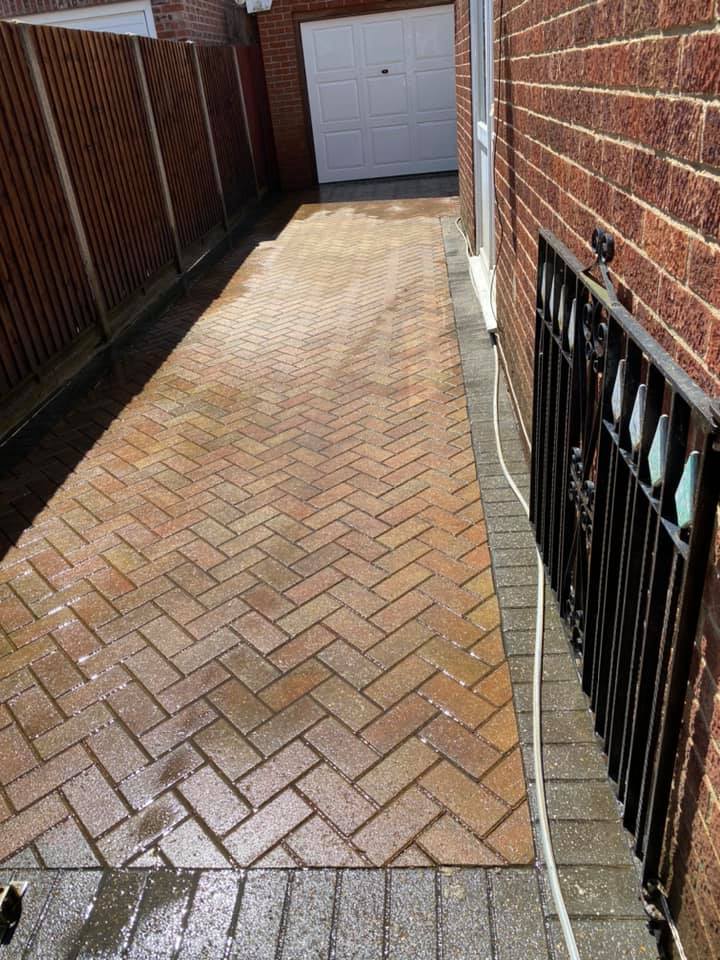 a brick driveway leading to a garage next to a brick building, before cleaning