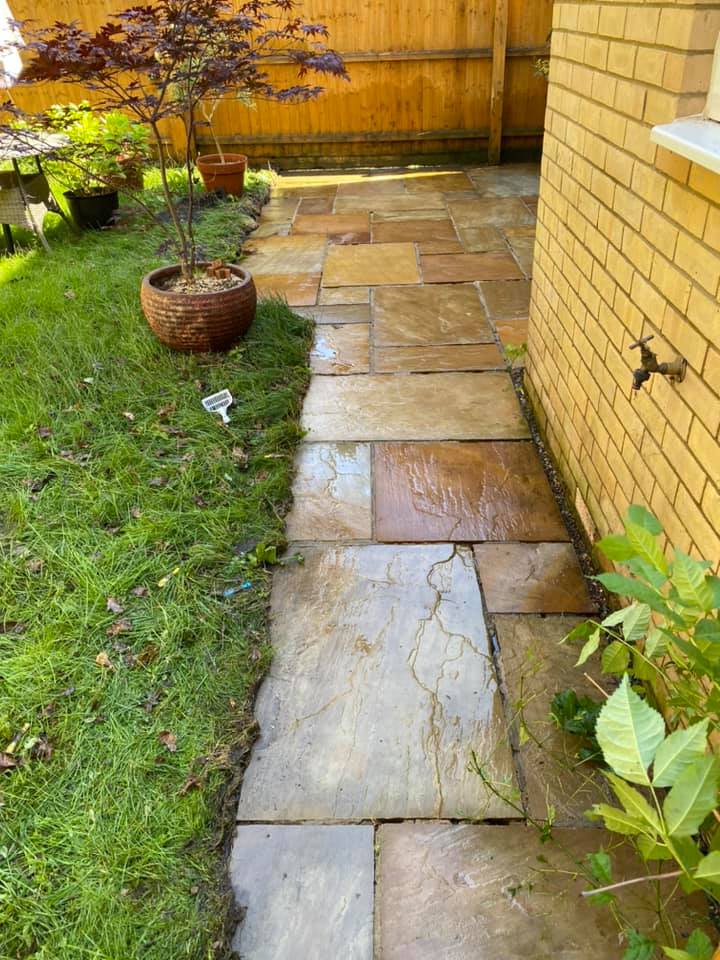 a stone walkway leading to a brick building in a backyard, after cleaning
