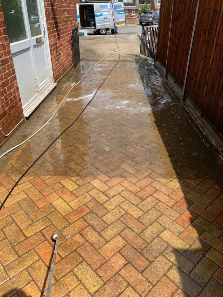a brick walkway is being cleaned with a pressure washer, after cleaning