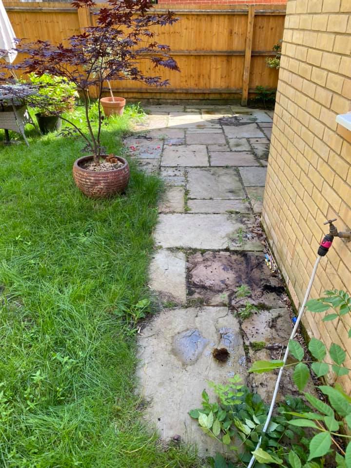 a brick house with a patio and a hose in the backyard, before cleaning