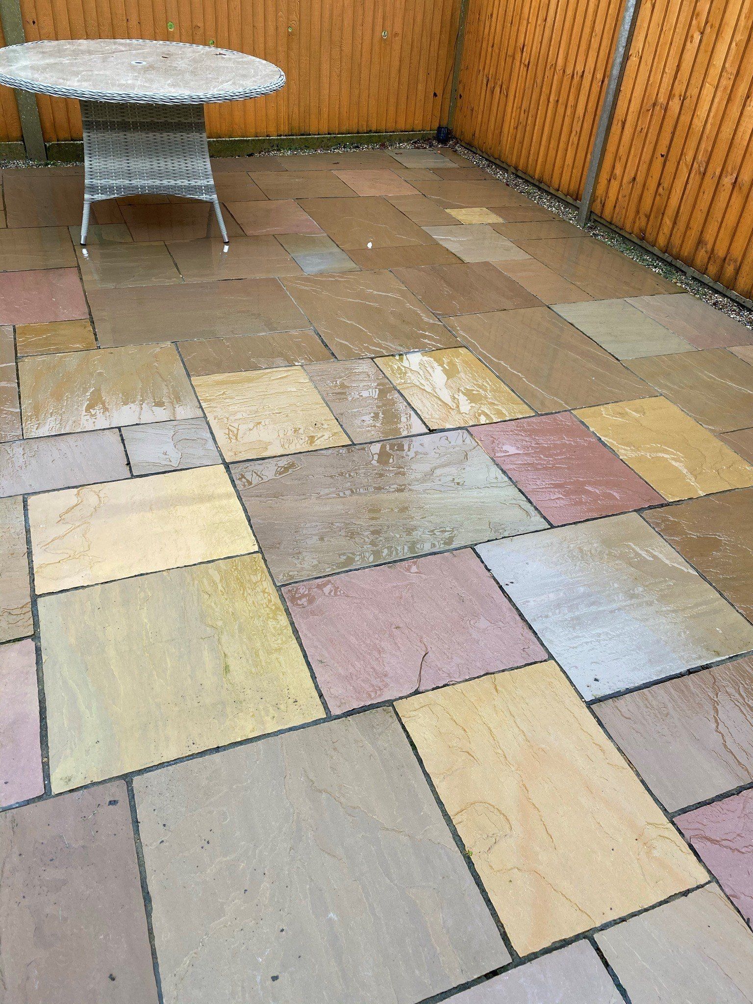 a patio with a table and chairs and a wooden fence, after cleaning