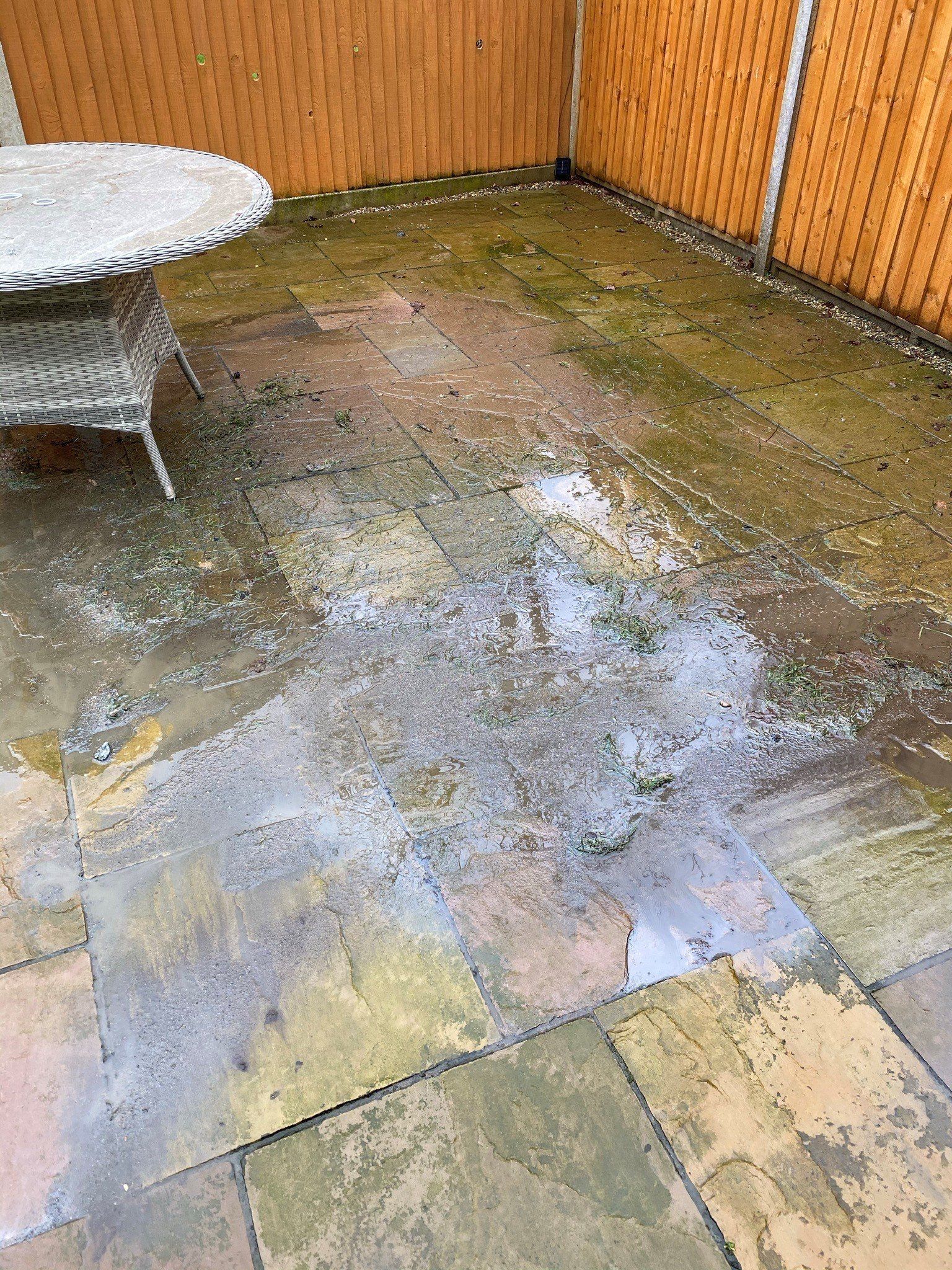 a patio with a table and chairs and a wooden fence, before cleaning