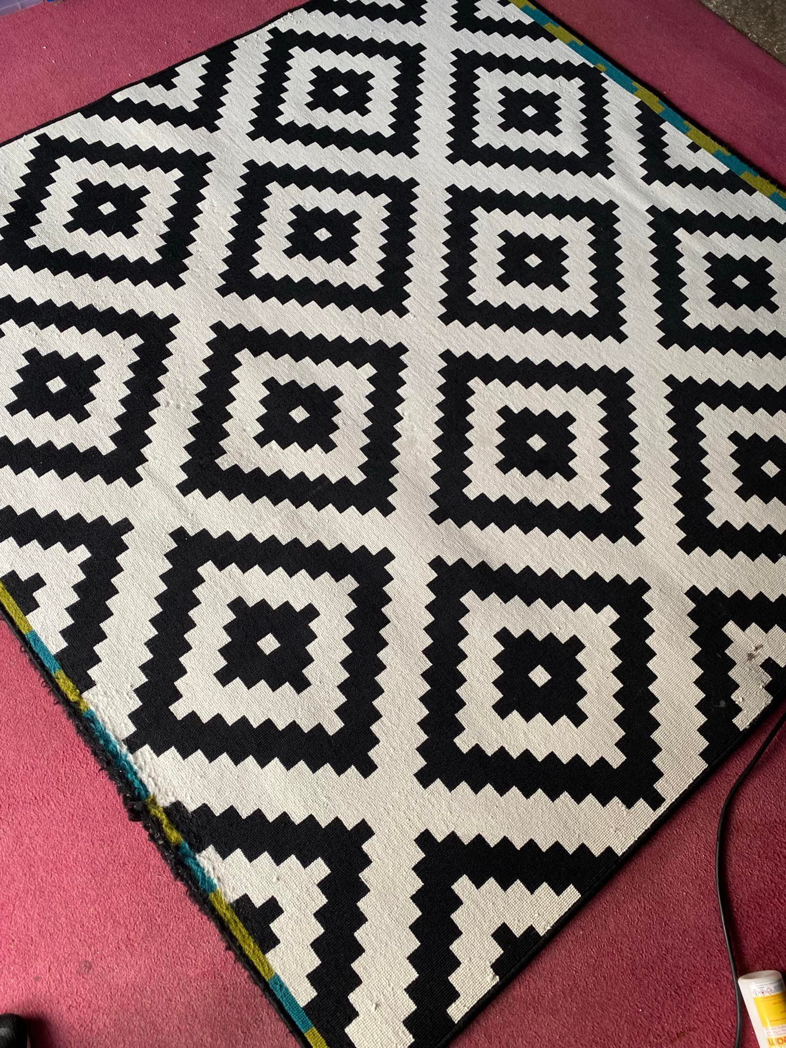 a black and white rug is sitting on a red carpet .