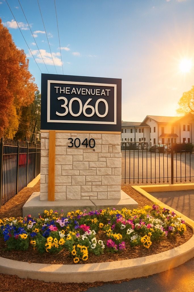 Entrance monument sign for The Reserve at 3060, with stone base and flower bed at sunset