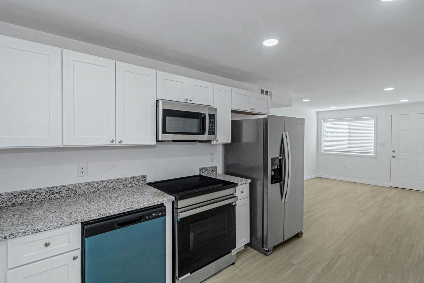Bright white kitchen with stainless steel appliances, granite counters, and light wood flooring