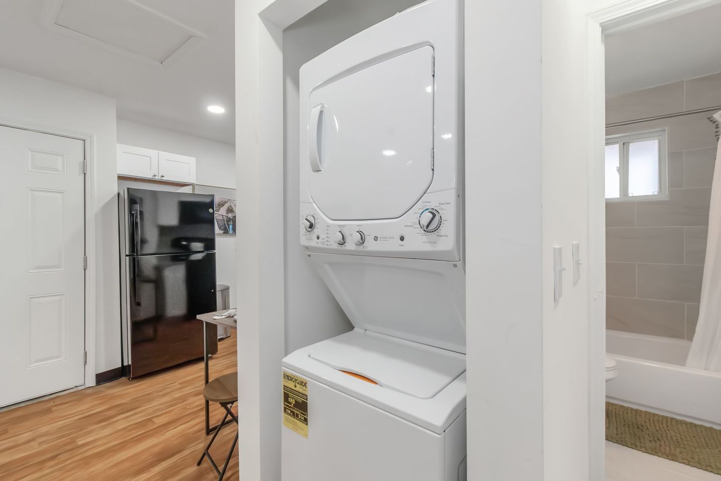 Laundry nook with stacked washer and dryer in a bright apartment hallway