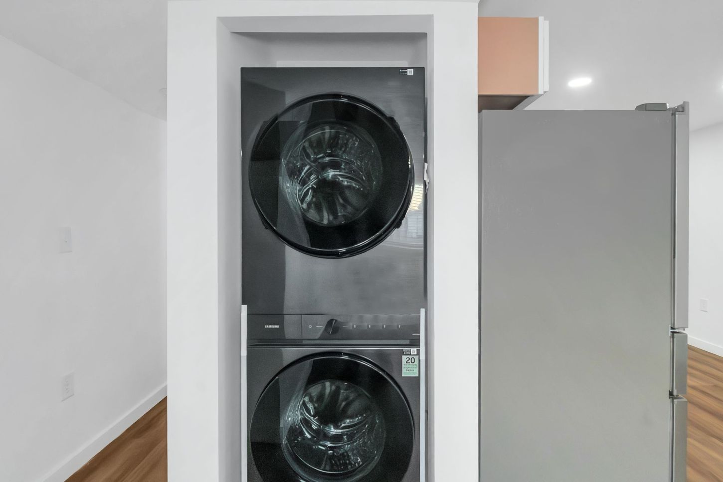 Stacked washer and dryer in a recessed closet, with a door open on the right.