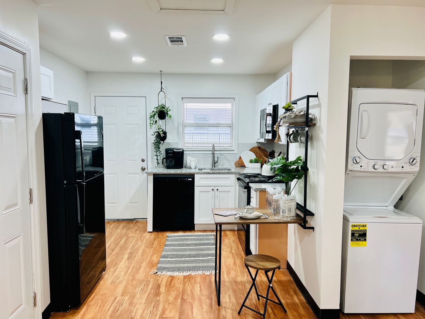 Bright kitchen interior with black appliances, white cabinets, and a small island with a stool.