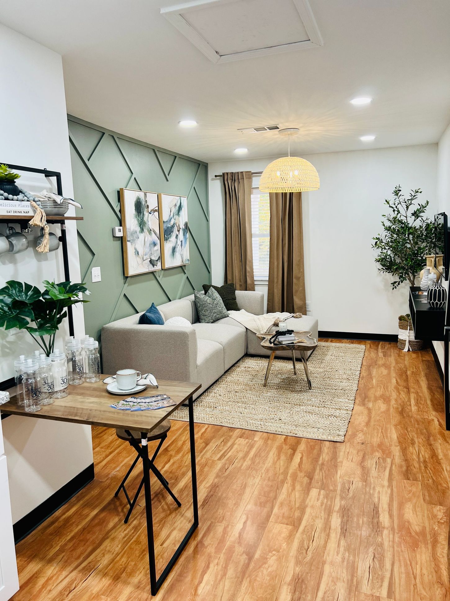 Cozy living room with gray sofa, woven rug, wood floors, plants, and soft lighting
