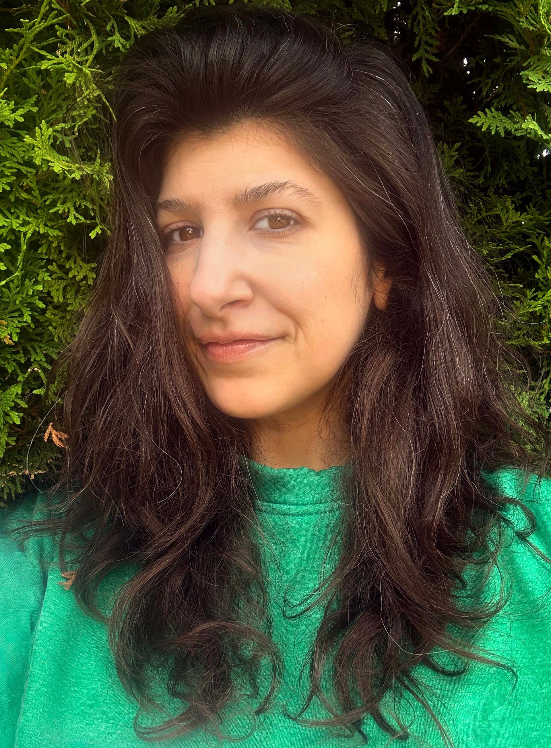 Headshot of cristina in green shirt against greenery