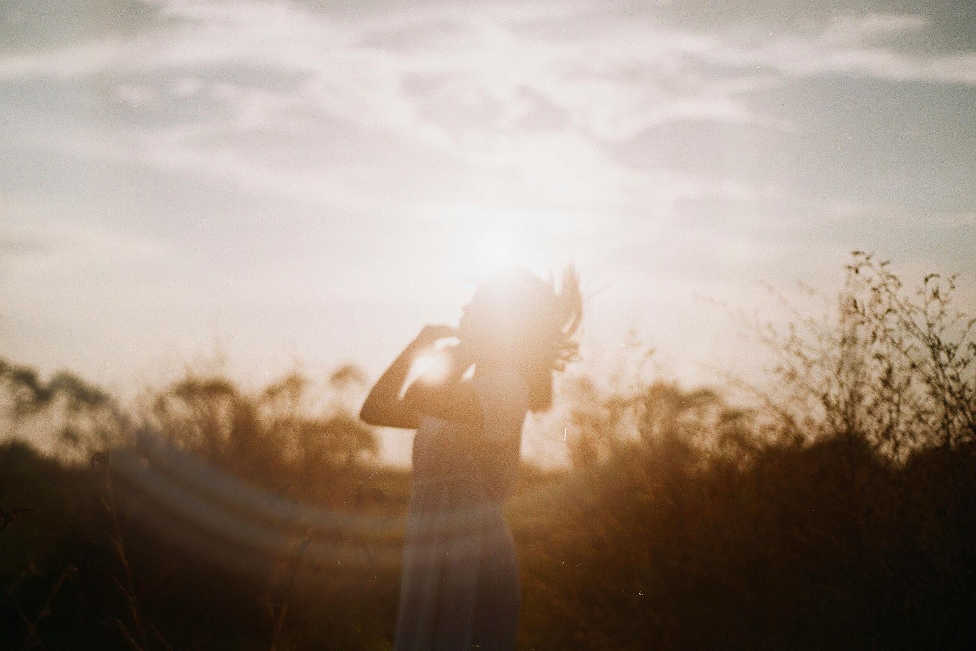 Person in a field against a bright sky