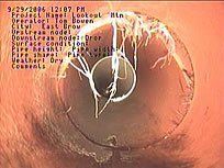 View inside a pipe with text overlay. Shows pipe condition, with rust and debris inside.