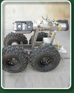Four-wheeled robot with large tires, metal frame, and equipment attached, likely for industrial use.