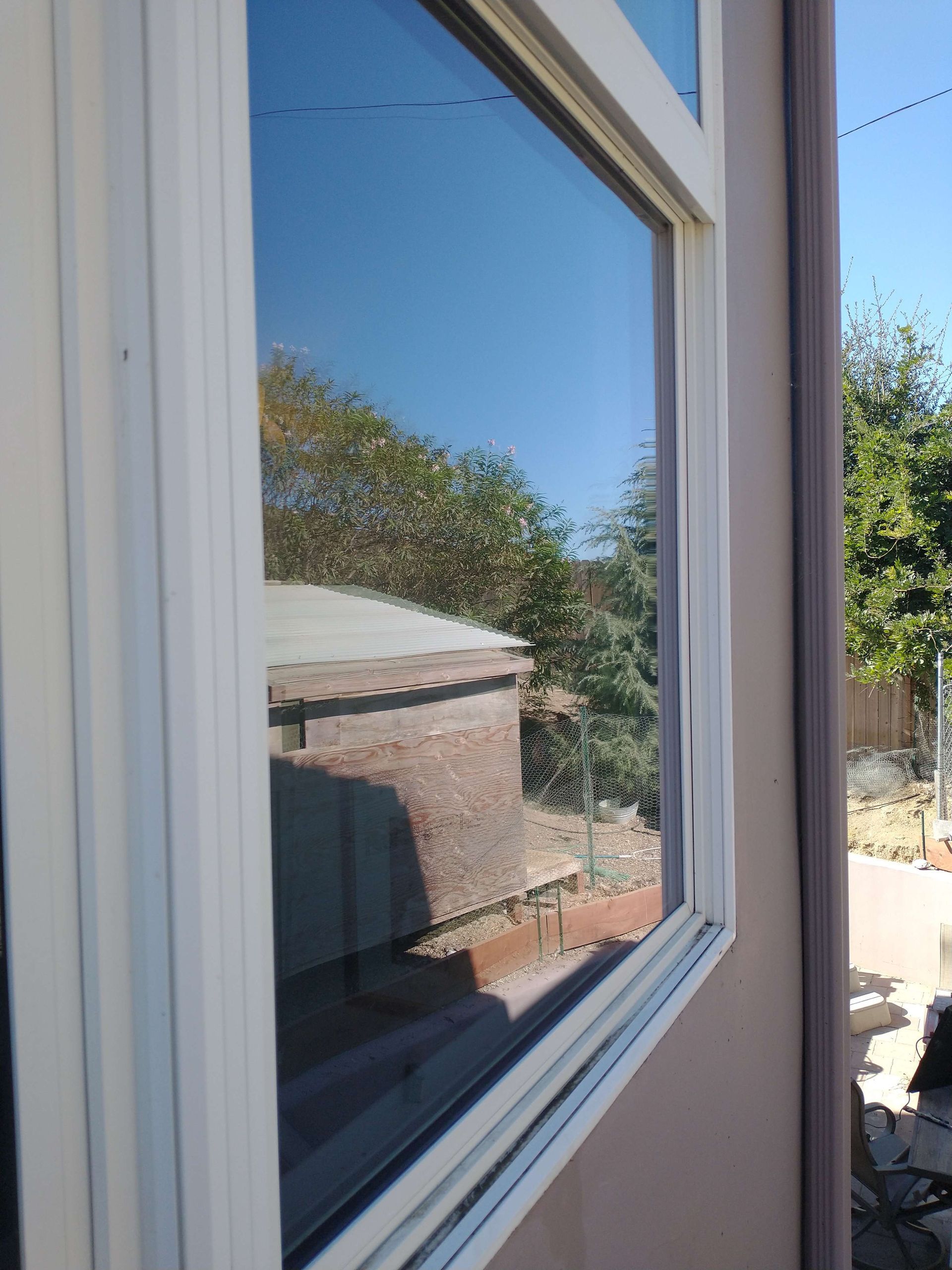 A window with a reflection of a house and trees in it