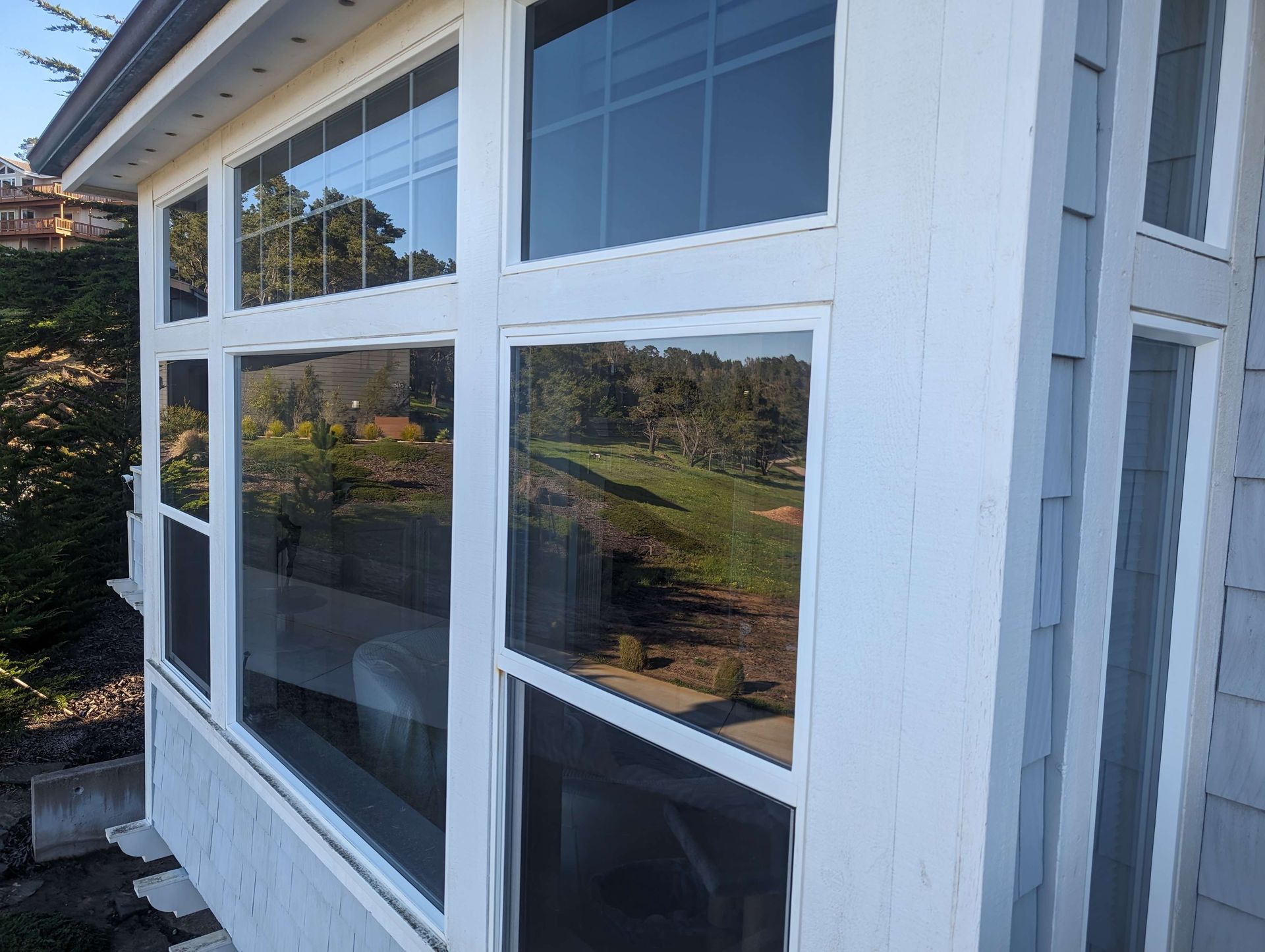 A white house with a lot of windows and a view of a golf course