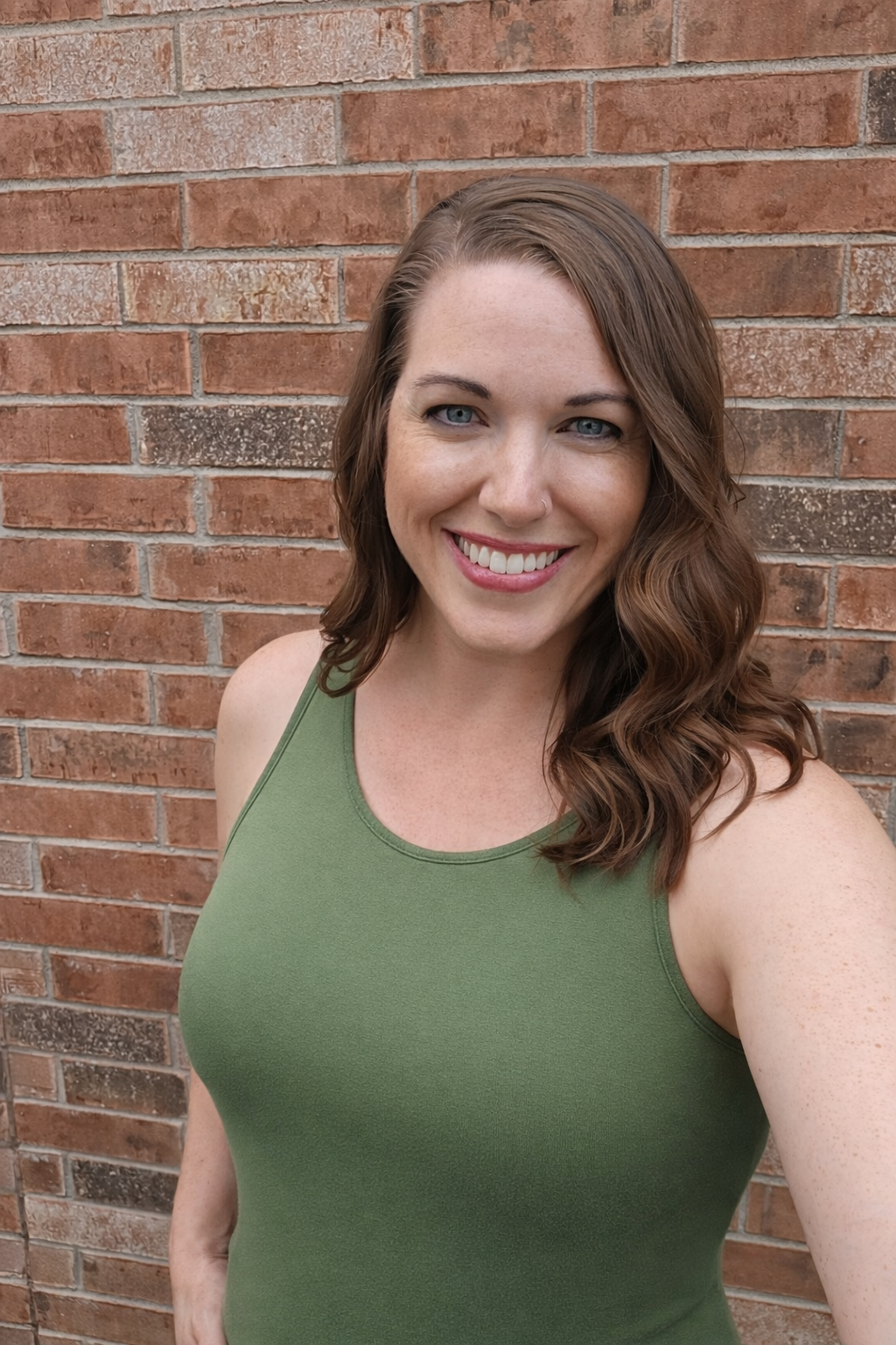 A woman wearing a green and white checkered shirt is smiling.