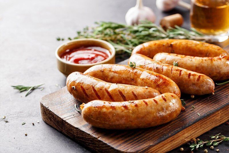 A Grilled Sausages on Wooden Board With Ketchup and Herbs — Paddock to Plate in Tamworth, NSW