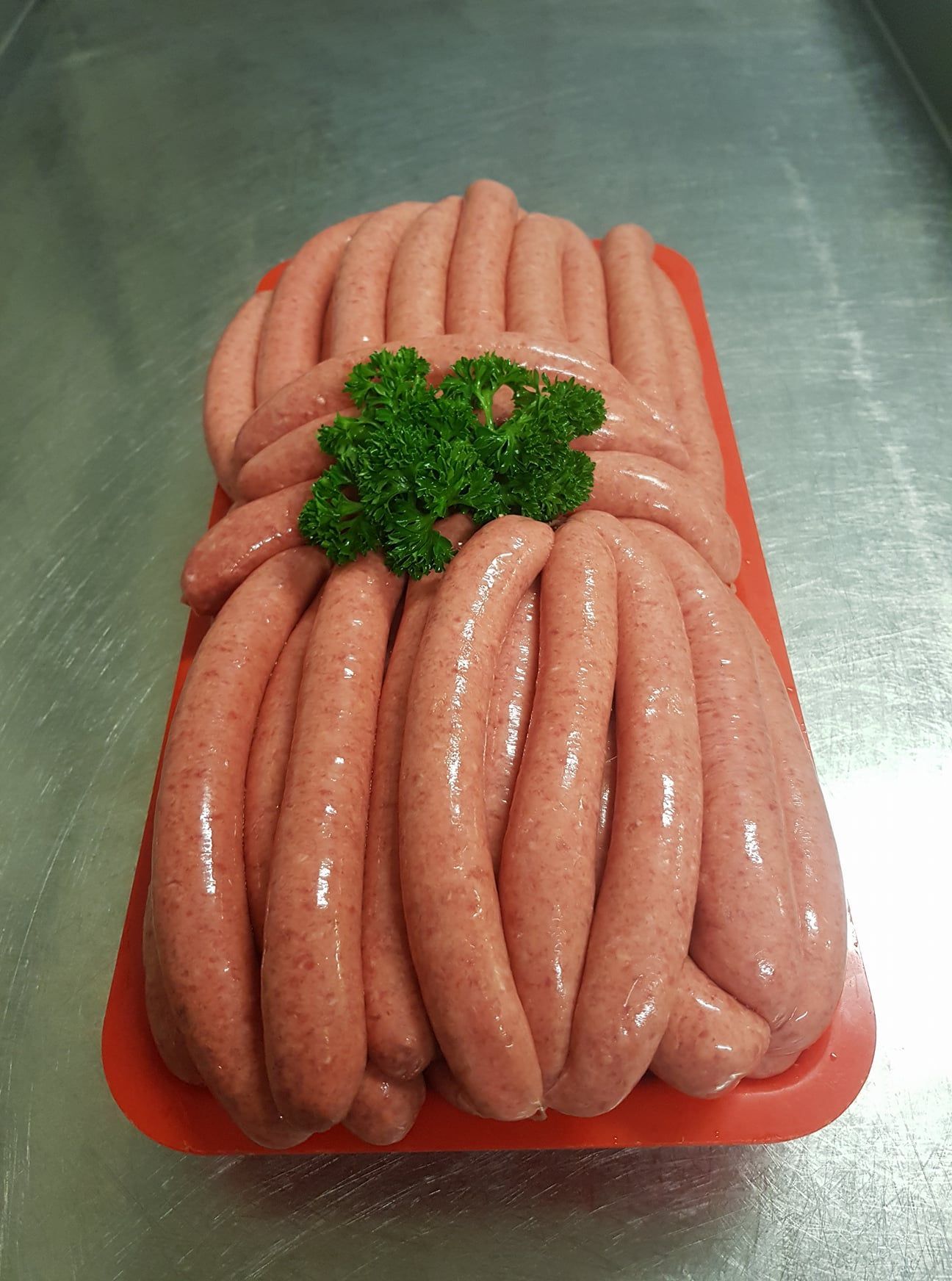 A Tray of Raw Pink Sausages, Topped With a Sprig of Green Parsley — Paddock to Plate in Tamworth, NSW