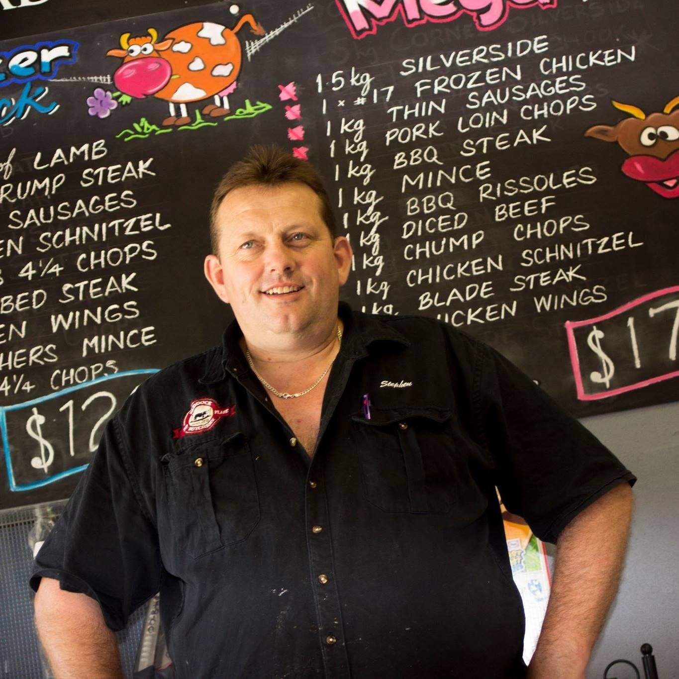 A Butcher Standing Near a Chalkboard Menu With Meat Options and Prices — Paddock to Plate in Tamworth, NSW