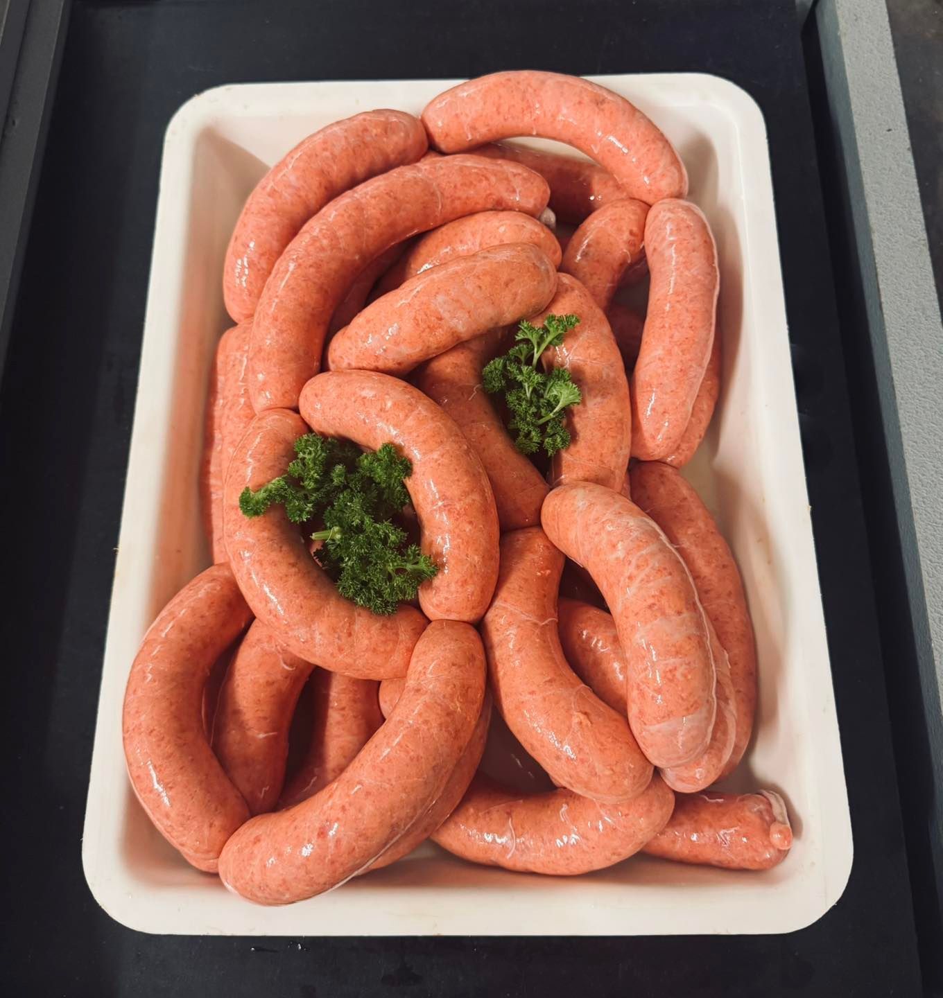 A Tray of Raw Pink Sausages, With Green Garnish — Paddock to Plate in Tamworth, NSW