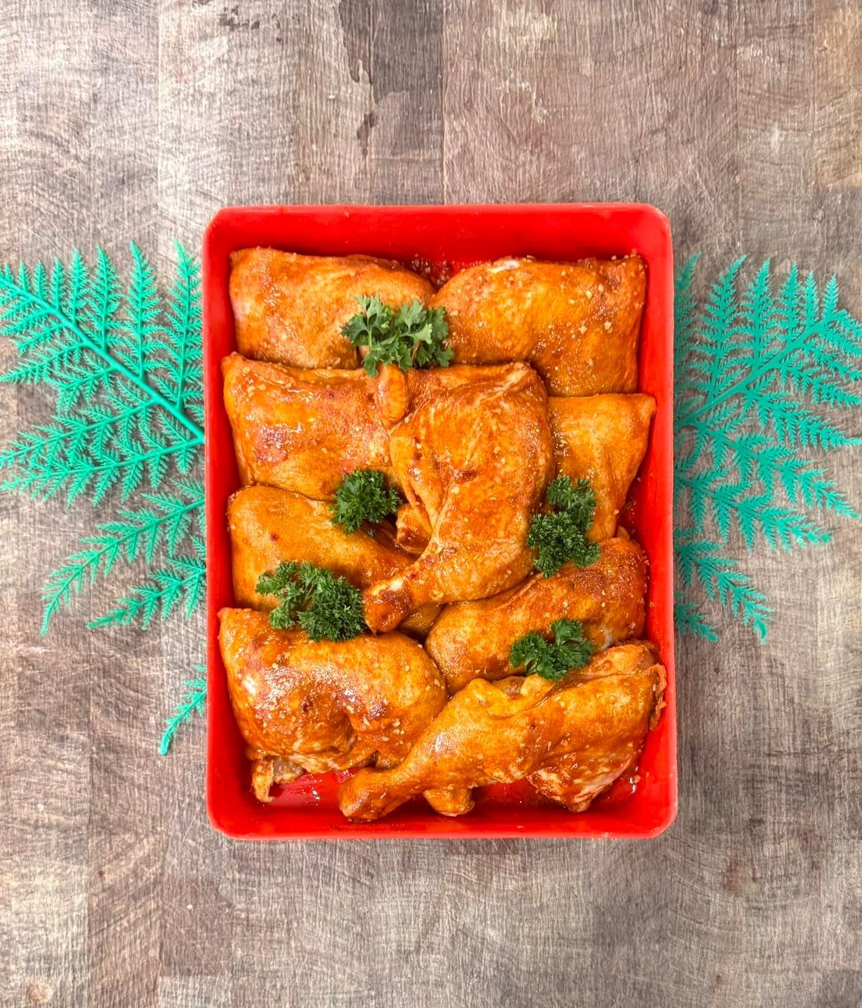 A Roasted Chicken Pieces in a Red Tray With Green Garnish on a Wood Surface — Paddock to Plate in Tamworth, NSW