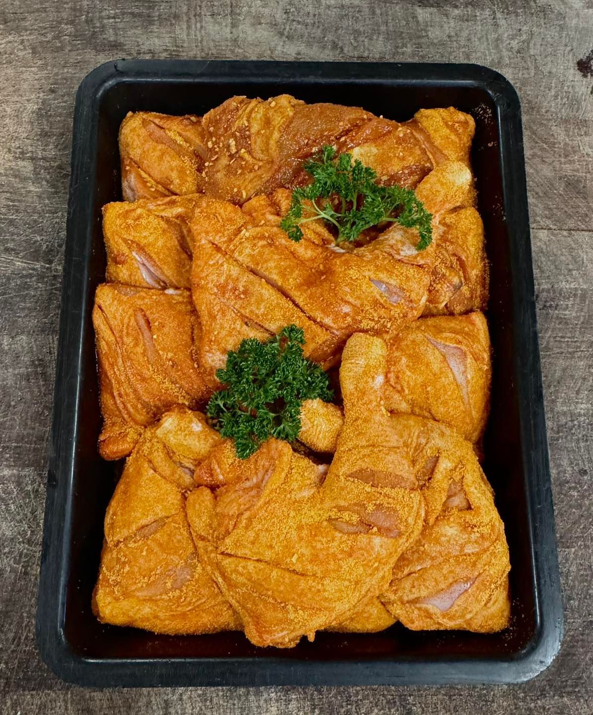 A Tray of Marinated Chicken Pieces, Reddish-orange in Colour, Garnished With Parsley — Paddock to Plate in Tamworth, NSW